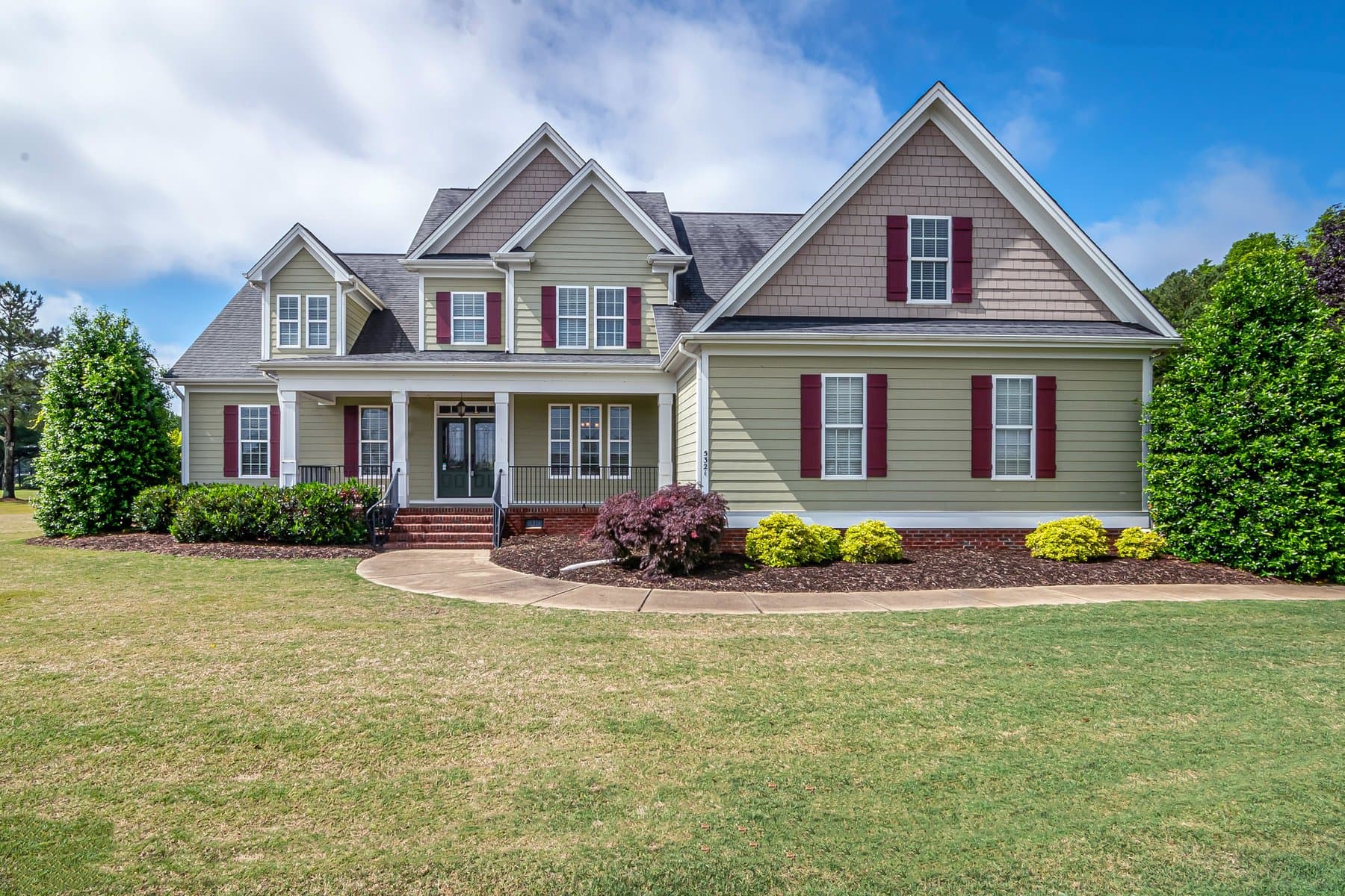 A suburban home exterior with warm tan siding and a manicured lawn under a clear sky