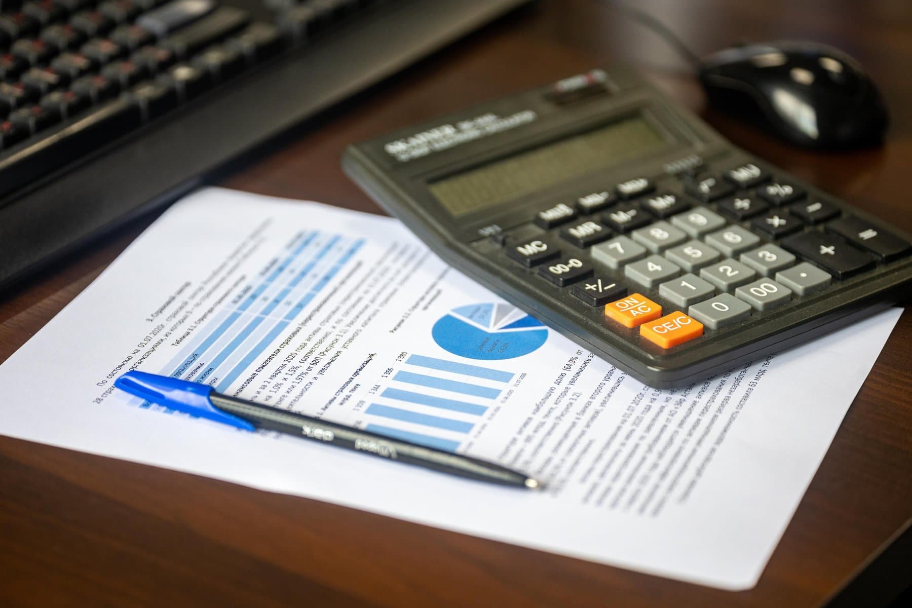A calculator and papers on a warm wood desk