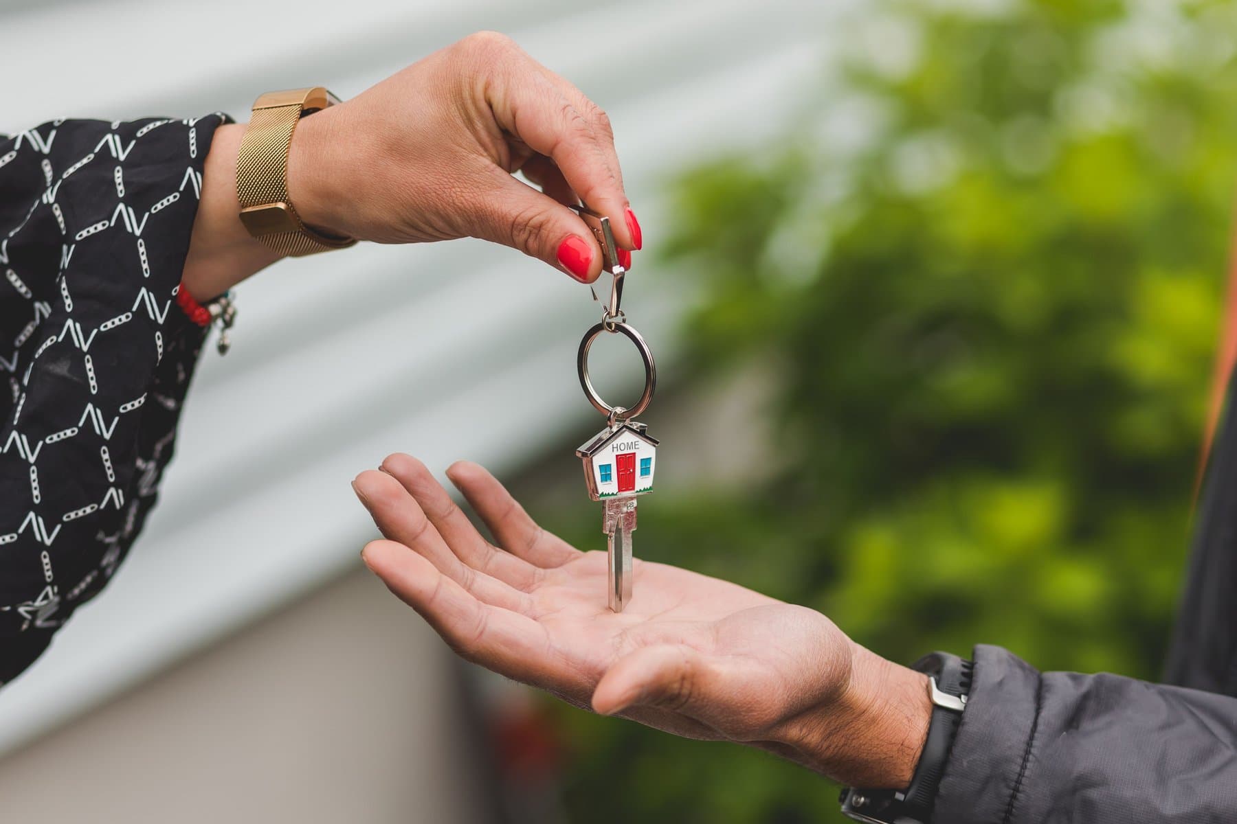 A hand holding a house-shaped keychain in a softly lit interior