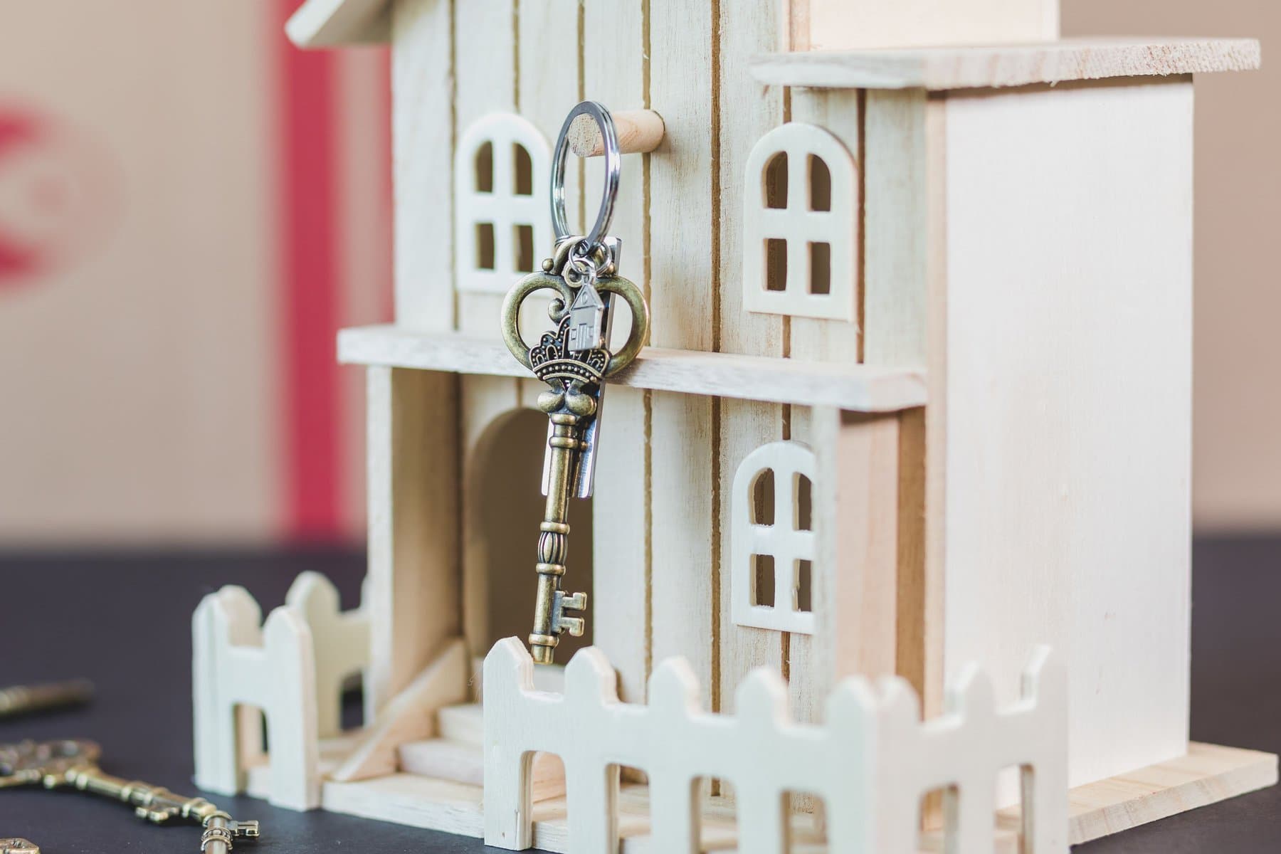 A vintage key hanging from a small wooden dollhouse model