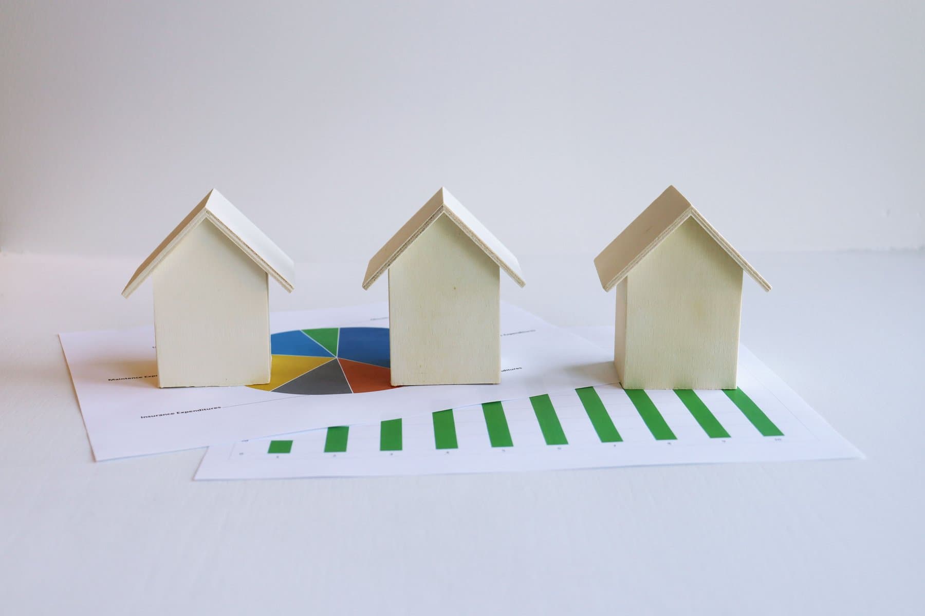 Small wooden house models on top of printed pie and bar charts
